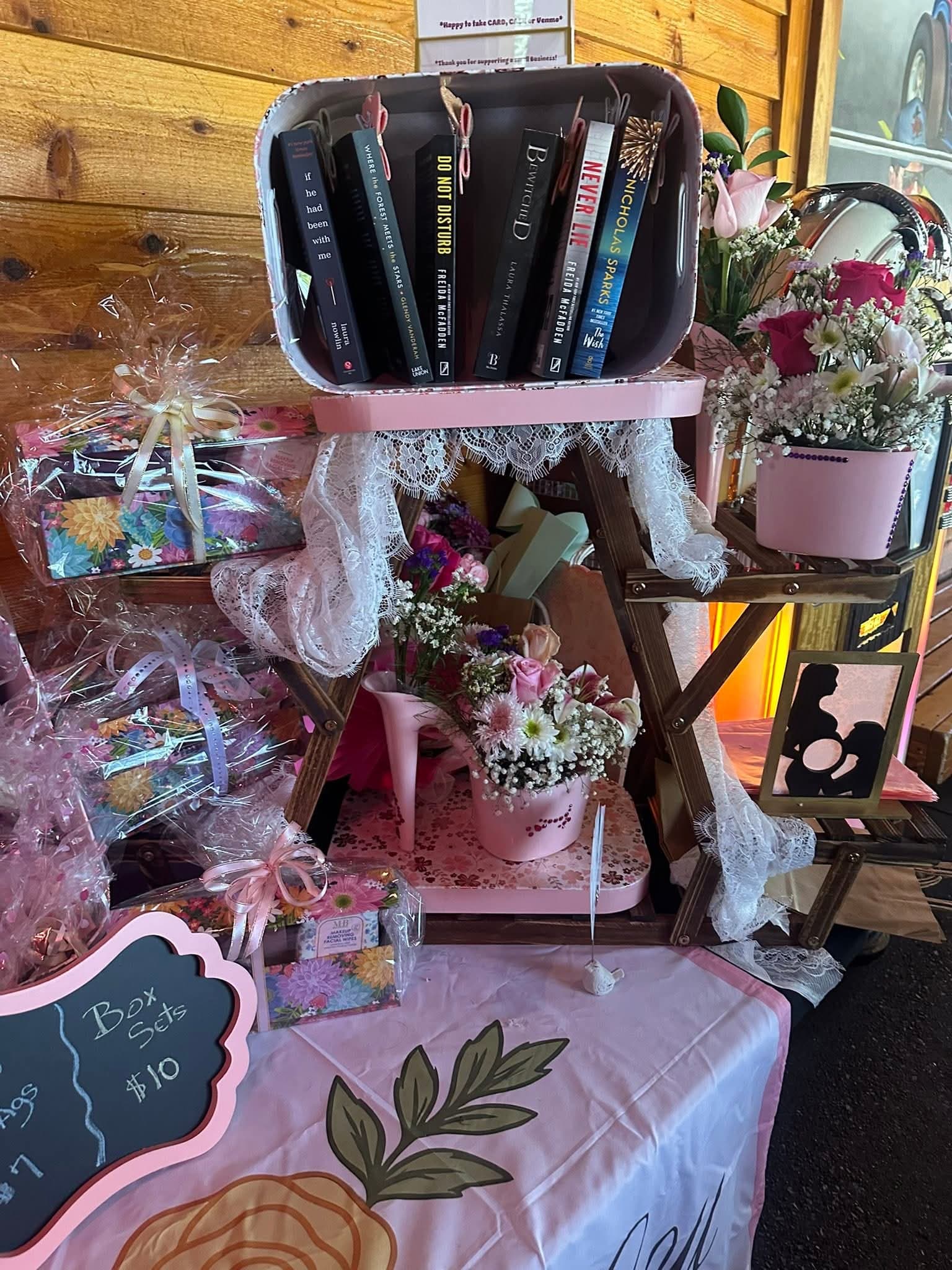 Vendor booth display with floral arrangements and gift items on a table.